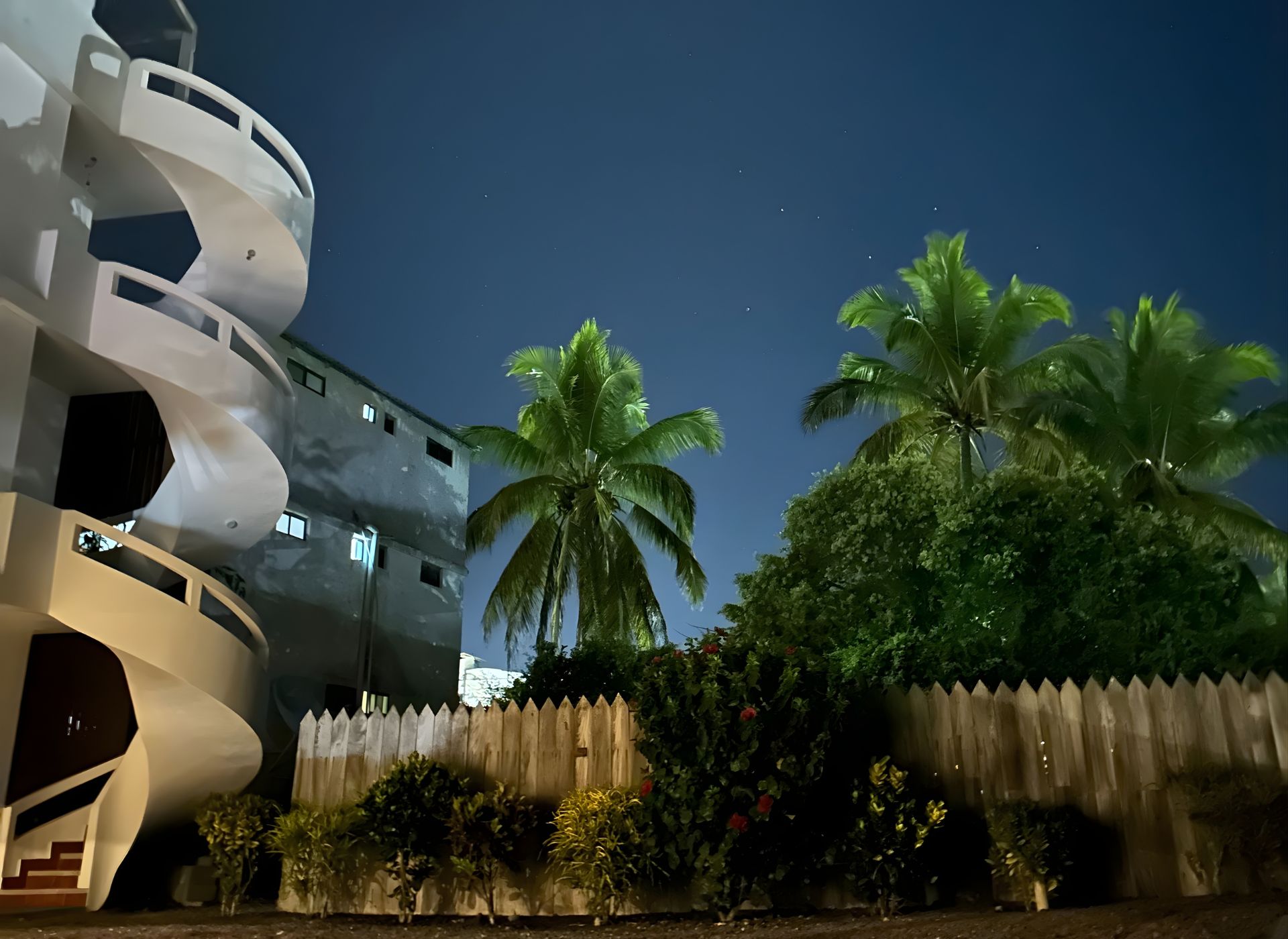 Vista nocturna del Hostal Jeniffer con palmeras